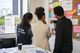 Entrepreneurs and an advisor collaborating in a community office, surrounded by project notes and everyday work details, with natural light creating a welcoming and authentic atmosphere.