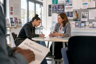 Resident consulting with staff at a community service desk in a sunlit Val-d'Oise office, natural and informal atmosphere.